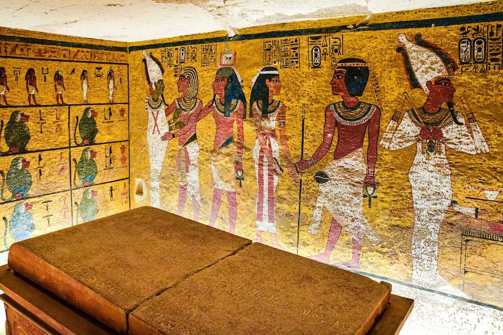 Interior of Tutankhamun's tomb KV62 in the Valley of the Kings, Luxor — vivid golden wall paintings showing ancient Egyptian gods - king tut tour curse