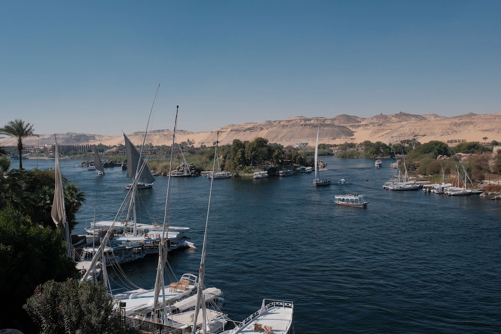Plan a trip to Egypt Traditional felucca sailboats on the Nile River in Aswan with the Eastern Desert cliffs in the background — Egypt