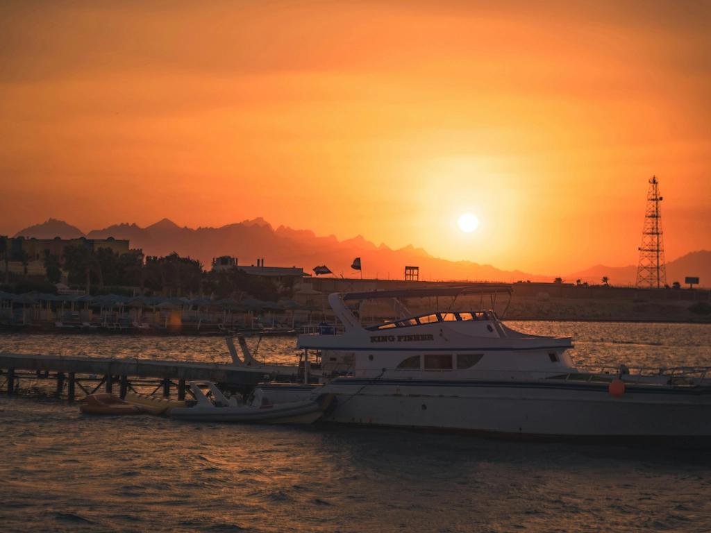 Plan a trip to Egypt Golden sunset over the Red Sea at Hurghada harbour with a boat in the foreground — perfect ending to an Egypt holiday