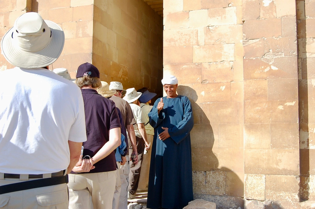 Local guide leading a small group of tourists through an ancient Egyptian temple - Egypt tour from USA