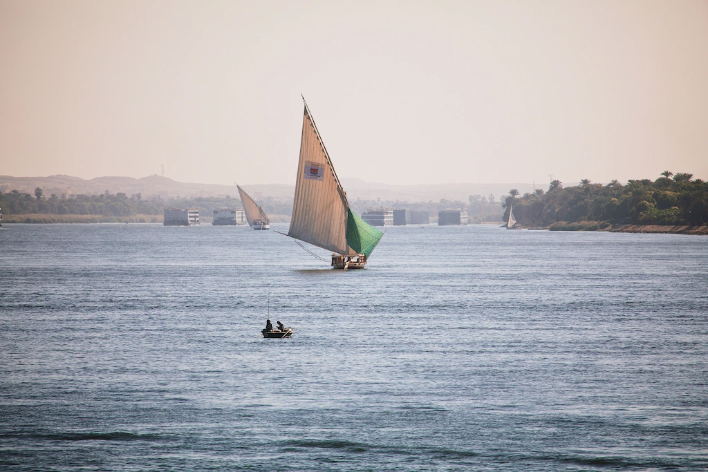 Upper Egypt Travel Guide - Traditional felucca sailboat gliding on the Nile River near Aswan's granite rocks