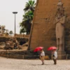 Upper Egypt Travel Guide - Tourists walking past the colossal statues at the entrance of Luxor Temple in Egypt