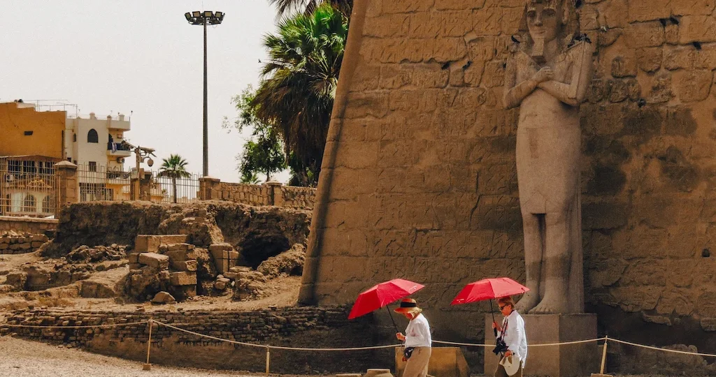 Upper Egypt Travel Guide - Tourists walking past the colossal statues at the entrance of Luxor Temple in Egypt