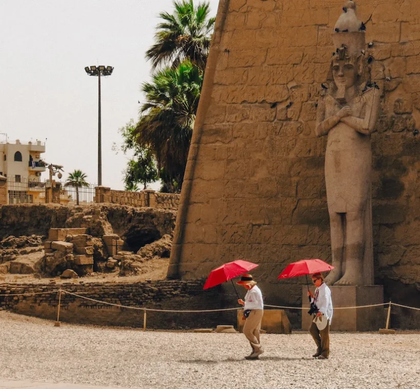 Upper Egypt Travel Guide - Tourists walking past the colossal statues at the entrance of Luxor Temple in Egypt