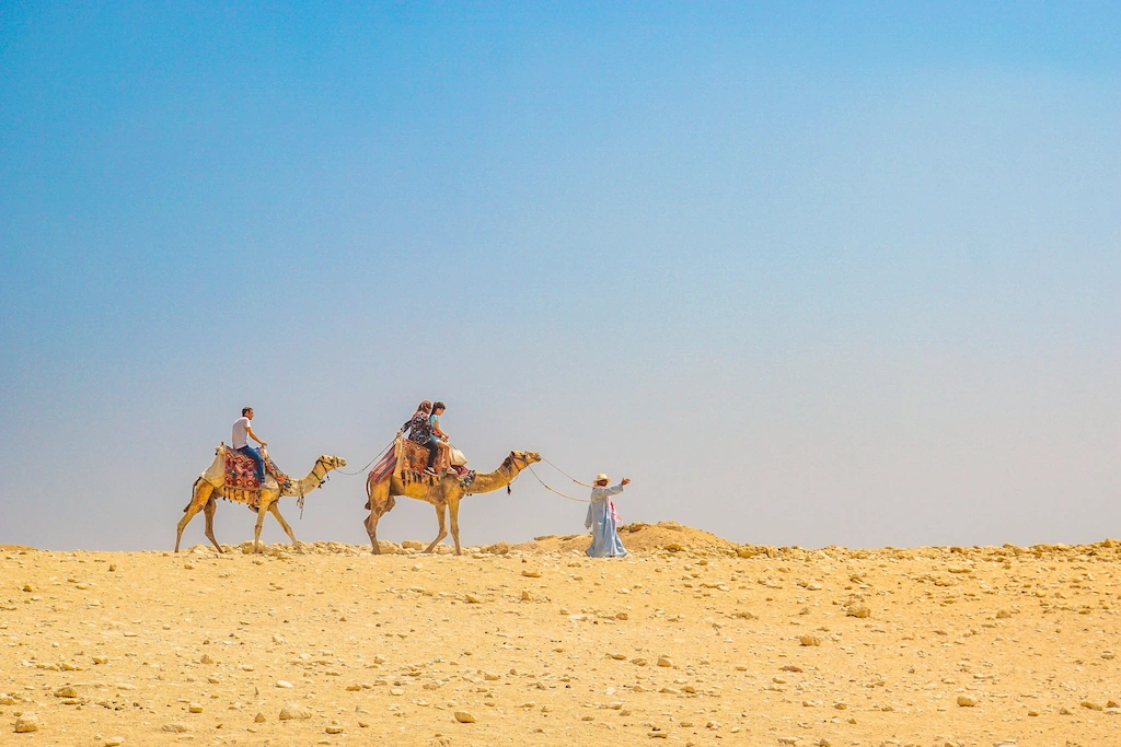 Local desert guide leading camel riders near the pyramids, echoing a Nile guide's field experience - Egypt Solar Eclipse Tour 