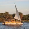 Dahabiya oder Nilkreuzfahrt – traditionelle Dahabiya unter vollen Segeln auf dem Nil zur goldenen Stunde