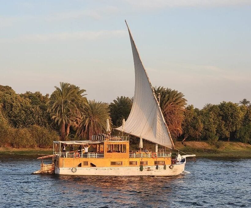Dahabiya oder Nilkreuzfahrt – traditionelle Dahabiya unter vollen Segeln auf dem Nil zur goldenen Stunde