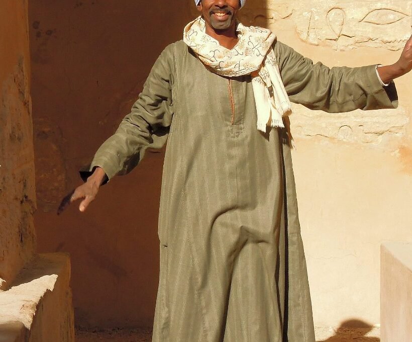 Egyptian traditional clothes: a man in an olive-green jellabiya standing in a stone doorway in Luxor