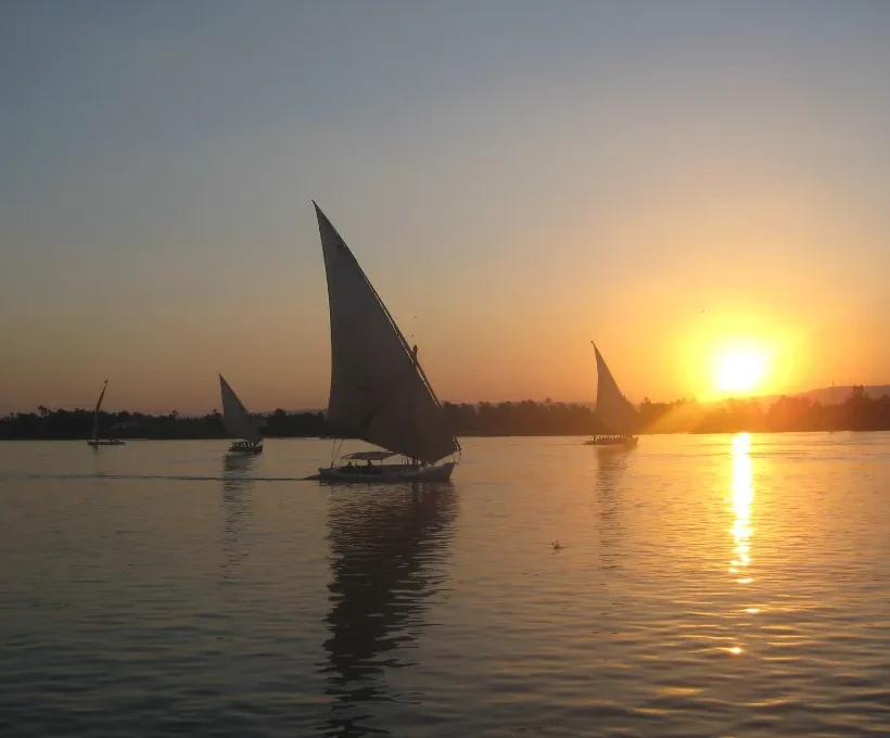 Felouque voguant vers un coucher de soleil doré sur le Nil, une scène classique d'escapade romantique à Noël en Égypte