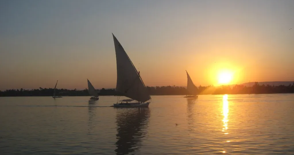 Felucca sailing toward a golden Nile sunset, a classic scene for romantic Christmas getaways in Egypt