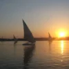 Feluke segelt in einen goldenen Sonnenuntergang auf dem Nil, ein klassisches Motiv für romantischen Weihnachtsurlaub in Ägypten